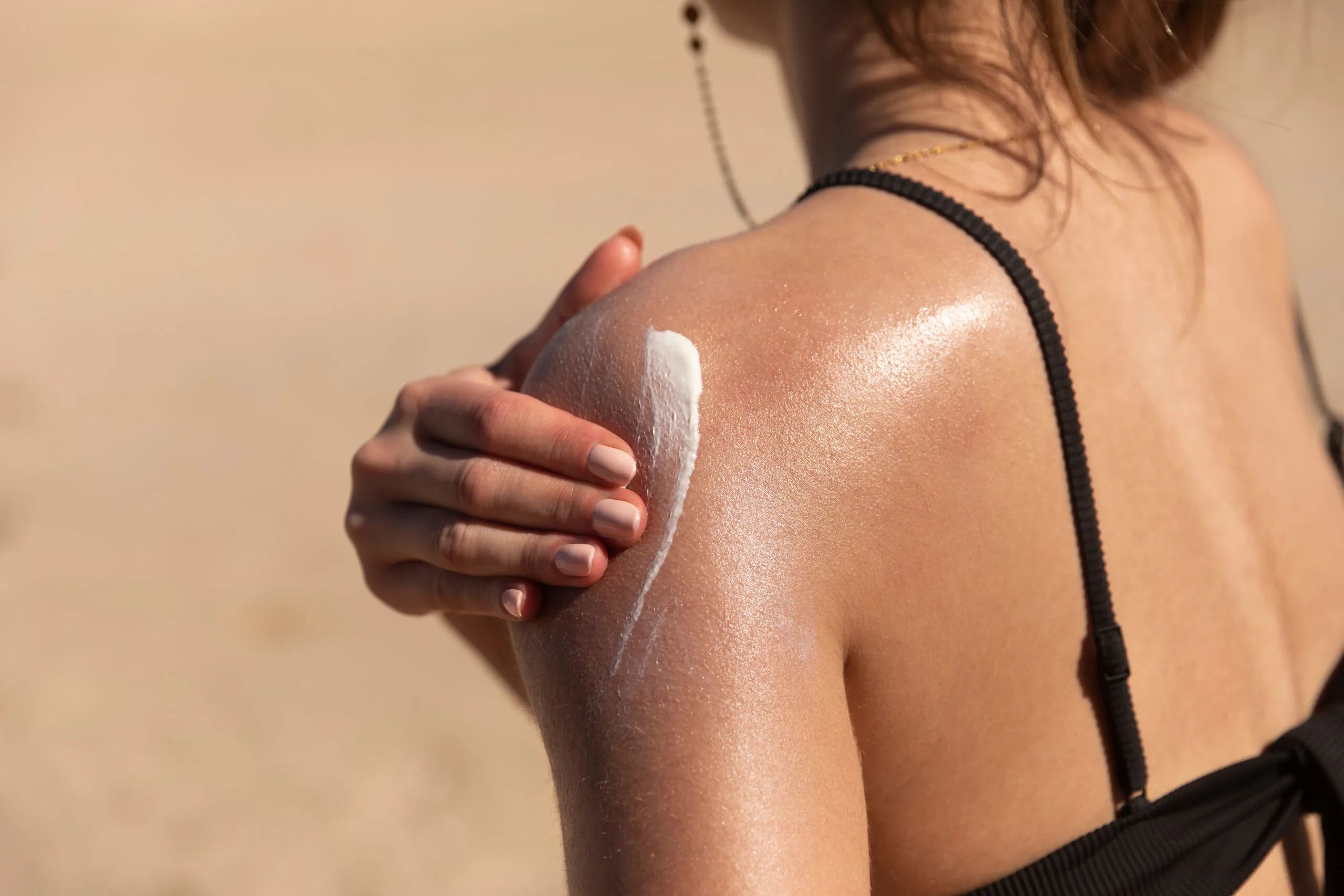 A young woman applying sun cream or sunscreen on her tanned shou AdobeStock 351934452 scaled
